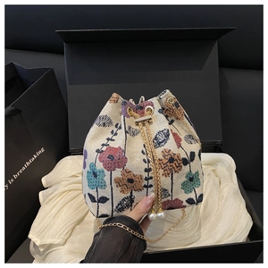 Détail du sac seau en jacquard floral avec cordon perlé et chaîne dorée dans un coffret cadeau