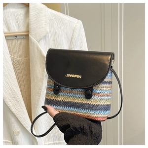 Détail du sac en paille tressée à rayures avec rabat en cuir noir et logo métallique