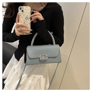 Close-up of light blue leather handbag featuring a sparkling rhinestone-encrusted G-buckle