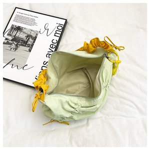 Detail of light green pleated nylon bag with yellow ruffles and spacious interior