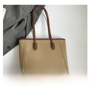 Macro shot of khaki leather tote with dark brown handles and premium stitching detail