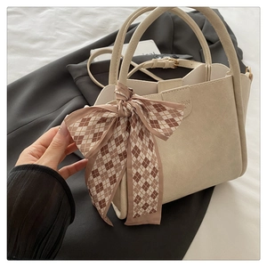 Detail of cream white matte leather bucket bag with silk scarf on handle and thin strap