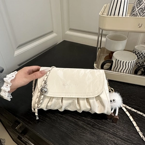 Détail du sac plissé crème avec chaîne argentée et pendentif en peluche blanche