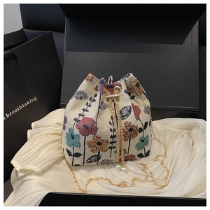 Détail du sac seau en tapisserie florale avec chaîne dorée et accents de perles