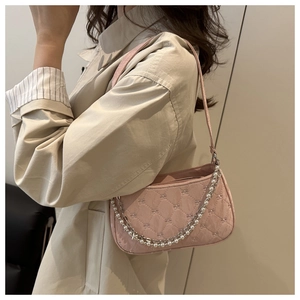 Détail d'un sac à bandoulière matelassé rose avec chaînes en perles et nœuds