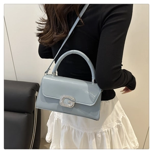 Detail of light blue patent leather crossbody bag with silver crystal buckle and top handle