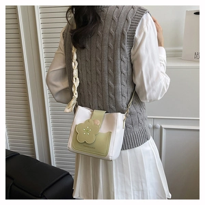 Detail of floral buckle and scarf chain strap on a green and white bucket bag