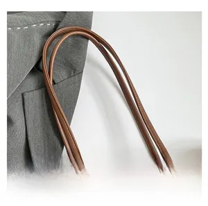 Close-up of brown leather shoulder straps with reinforced stitching on a khaki tote bag