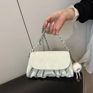 Détail du sac plissé blanc avec bandoulière chaîne et pendentif monstre en peluche