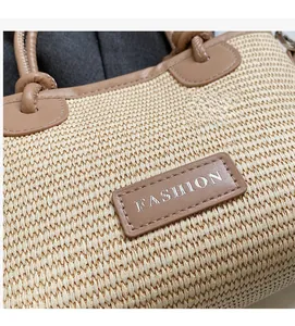 Detail of straw woven tote bag showing brown PU leather tag with FASHION text and texture