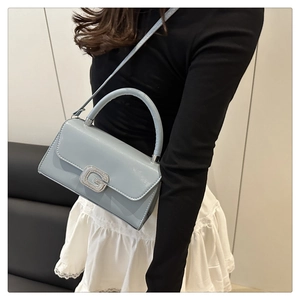 Detail einer hellblauen Lackledertasche mit einer funkelnden silbernen G-förmigen Schnalle