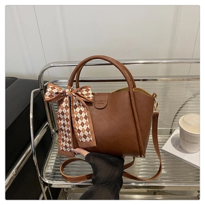 Close-up of brown vintage bucket bag with plaid silk scarf and JINGPIN embossed text