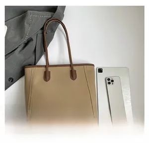 Detailed side view of a beige tote bag showing stitching and brown leather handles