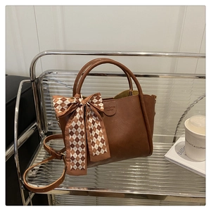 Close-up of a dark brown bucket bag with a stylish plaid bow and brand embossing