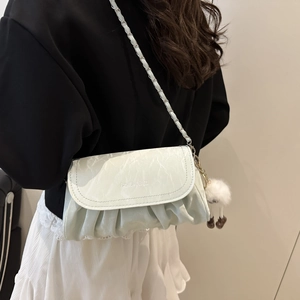 Détail du sac bandoulière plissé vert clair avec chaîne et breloque agneau en peluche