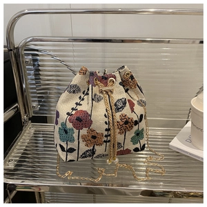 Vue détaillée du sac seau tissé à fleurs avec cordon perlé et chaîne dorée