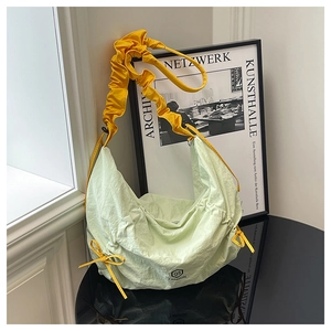 Detail of light green pleated nylon crescent bag with bright yellow ruffled shoulder strap