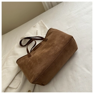 Detailed macro shot of caramel brown suede tote bag with FANYISSA BAGS logo patch