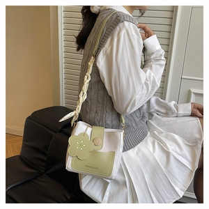 Chic green and white crossbody bucket bag with floral charm and silk scarf handle detail