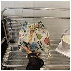 Détail de la broderie florale et cordon perle sur sac seau en lin beige avec chaîne dorée