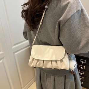 Détail du sac bandoulière plissé blanc cassé avec chaîne et breloque pelucheuse