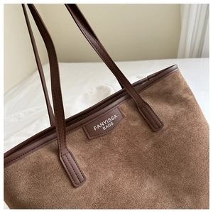 Detail of vintage brown tote bag showing textured suede fabric and leather brand label