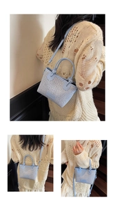 Detail view of woven straw crossbody bag in light blue and white with round handle