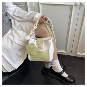 Detail of white and green bucket bag with floral charm and silk scarf handle detail