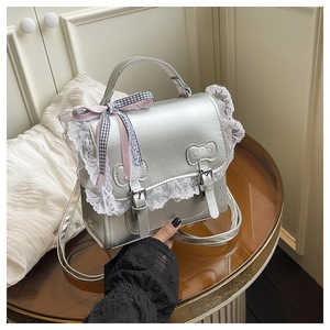Dettaglio ravvicinato della borsa in pelle PU argento con bordo in pizzo bianco e fiocchi