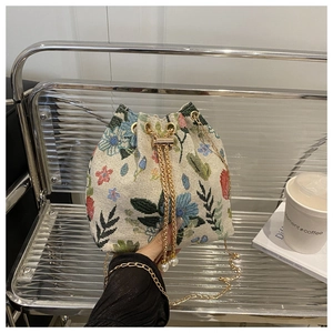 Détail du sac seau à broderie florale avec chaîne dorée et pendentif en perle