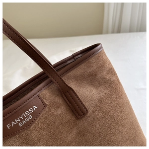 Detail shot of vintage brown tote bag with suede texture and leather brand tag