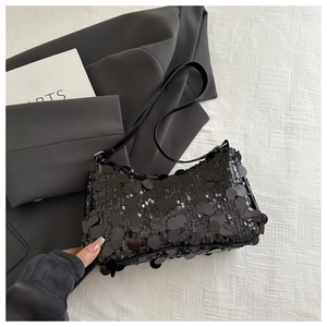 Dettaglio delle paillettes nere scintillanti e della tracolla in pelle della borsa