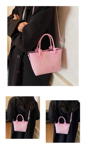 Detail view of pink woven bucket bag with leather top handle and crossbody strap