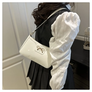 Dettaglio borsa baguette bianca con fibbia decorativa a fiocco dorato in stile retrò