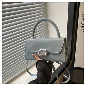 Detail of light blue patent leather handbag featuring a crystal-encrusted G buckle