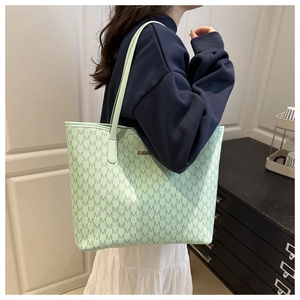 Vue latérale du grand sac cabas vert clair avec motifs M et fines bretelles en cuir