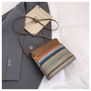 Detailed close-up of rainbow striped straw woven bucket bag with brown leather flap