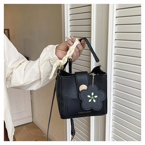 Detail of black leather bucket bag with silk scarf handle and flower pendant charm