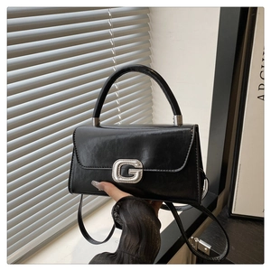 Detail of black leather handbag featuring silver G buckle with rhinestones and handle