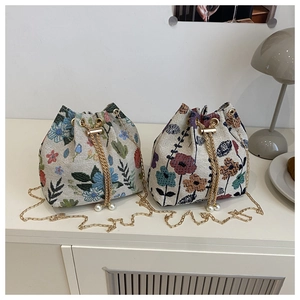 Détail du sac seau en jacquard floral avec bandoulière dorée et finitions en perles
