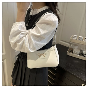 Dettaglio borsa baguette bianca lucida con fibbia metallica a fiocco dorato elegante