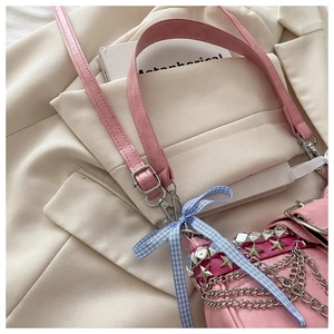 Détail du sac Y2K rose avec clous métalliques en étoile et un nœud à carreaux bleus