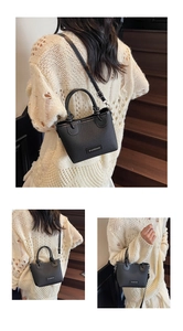 Detail of black woven crossbody bag with leather trim on a wooden background