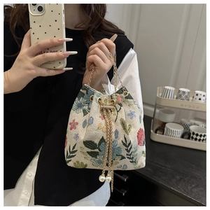 Detail of floral tapestry bucket bag featuring gold chain and pearl drawstring charms