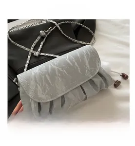Detail of light blue ruched cloud bag with silver chain strap and printed brand text