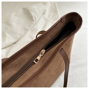 Detail view of the brown suede tote bag featuring a smooth metal zipper and leather trim