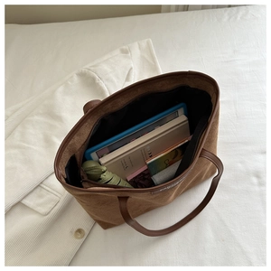 Interior view showing the large capacity for iPad and books in the brown tote bag