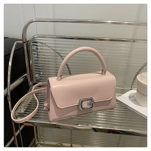Detailed macro shot of light pink leather bag featuring a sparkling rhinestone G buckle