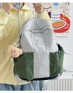 Detail showing two-tone nylon fabric with brand embroidery and a cute plush bear pendant