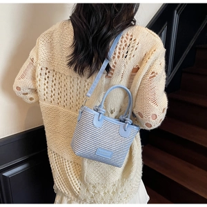 Close-up of blue and white woven handbag with leather straps and Fashion label detail